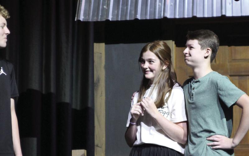 Harper Beasley as Tevye, Evi Bussell as Tzeitel, and Kyzer Gaither as Motel rehearse a scene of “Fiddler on the Roof Jr.” during the Cushing Theatre Camp on July 17. After being directed that “he was supposed to be in love” by Kristin Tarp, Gaither hurriedly placed his arm around Bussell and held back a laugh.