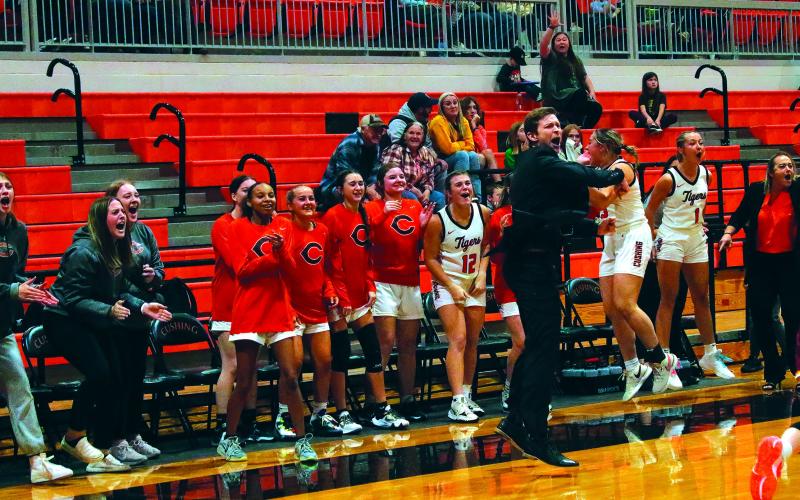 The Lady Tiger bench along with head Coach Mason Baade erupts in cheers after Ella Nanaeto drains a late-game three to give Cushing the lead. Photo by J. D. Meisner