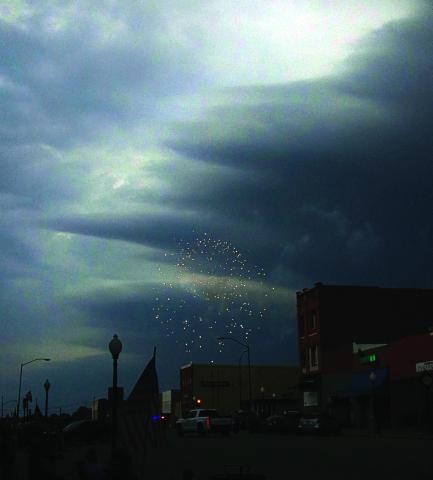 A firework explodes over downtown Cushing Saturday evening as storm clouds darken the sky. The Cushing fireworks show was moved up to 7:15 p.m. on the Fourth of July due to a severe thunderstorm rolling in. Photo by Allie Prater