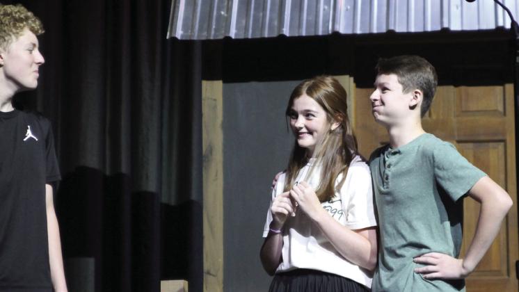 Harper Beasley as Tevye, Evi Bussell as Tzeitel, and Kyzer Gaither as Motel rehearse a scene of “Fiddler on the Roof Jr.” during the Cushing Theatre Camp on July 17. After being directed that “he was supposed to be in love” by Kristin Tarp, Gaither hurriedly placed his arm around Bussell and held back a laugh.