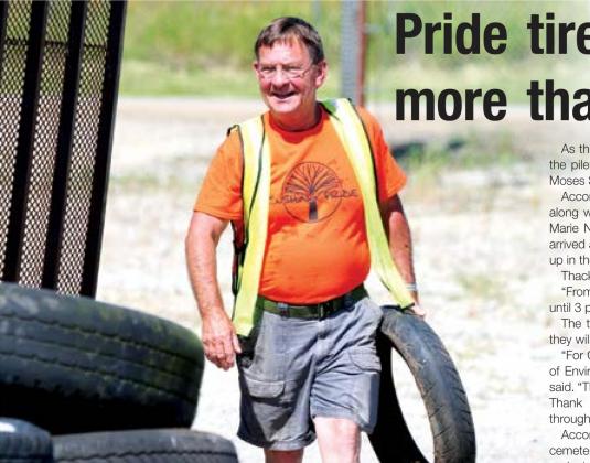John Moran unloads a motorcycle tire from a trailer during Cushing Pride’s tire recycling event Saturday.