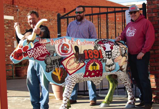 John Moran, Tyler Stein and Justin Cargill show off the Downtown Cushing Revitalization Association’s longhorn steer which they installed at Centennial Park in Cushing last Friday. The artwork on the steer, painted by Stein, depicts historical highlights from Cushing’s past on one side and highlights from the oil industry on the other. Photo by J. D. Meisner
