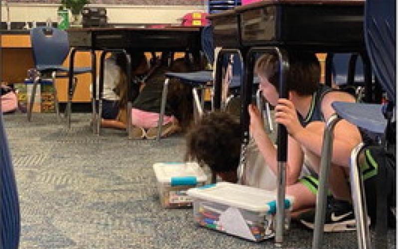 Fourth-grade students at Plaza Towers Elementary School in Moore practice Drop, Cover and Hold On under their desks during an earthquake safety presentation by the Oklahoma Geological Survey on Wednesday, Oct. 9, 2024. Courtesy of ODEM