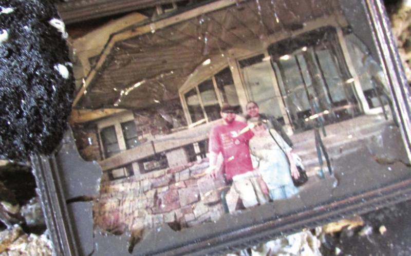 Above: A picture of Fincher, his grandma and Jessica at Queen Wilhelmina State Park lay atop a destroyed couch after a fire caused the image to fall from the wall.