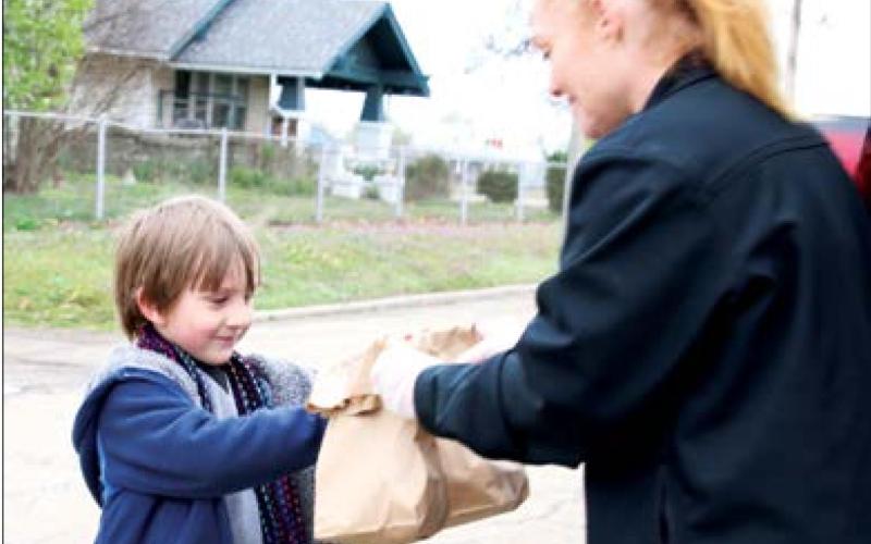 Liger Phelps receives his breakfast and lunch sacks from Keystone Food Services employee Kristy Barnes at Cushing Upper Elementary Monday. Close to 400 meals were provided at two separate sites in Cushing.