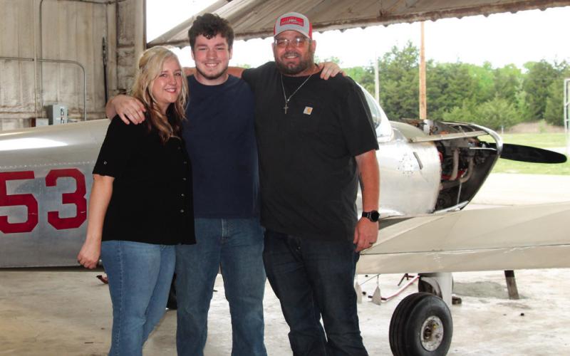 Jacob O’Kelley stands between his parents — Jazmine and Jack — in front of a small single engine aircraft.Photo by DeAnna Maddox.