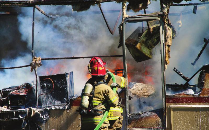 Members of the Cushing Fire Department work to extinguish a burning RV on East Vine, last week. Photo by Allie Prater