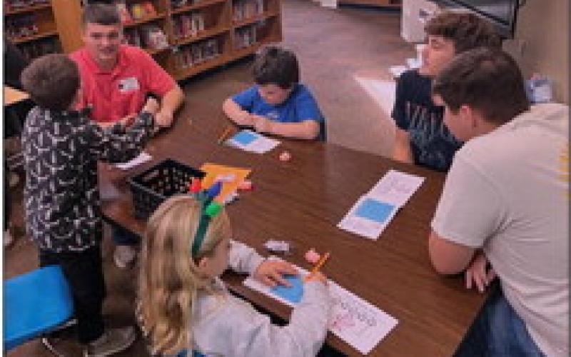 Cushing High School students Cason Brandon, Tommy Rolfe, and Tyler Norman work with second graders to figure out the best house to withstand the Big Bad Wolf’s huffs and puffs.