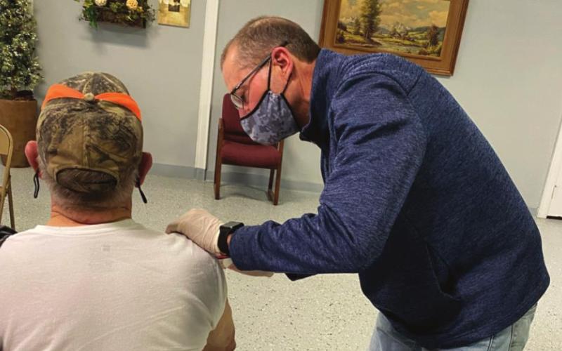 John Lemley, pharmacist at Baker Pharmacy, administers the COVID-19 vaccine to patient Hubert Bowley.