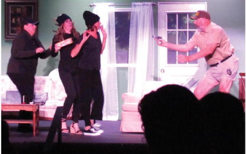 Sheriff Grover Lout (Brett Anderson) tells Verdeen Bodeen (Lisa Stevens), Peaches Verdeen-Belrose (Regina Brown), and Jimmie Wyvette Verdeen (Linda Swanner) to freeze after they were caught Velveeta handed in the Cushing Community Theatre’s performance of “The Red Velvet Cake War” directed by Christina Chestnut.