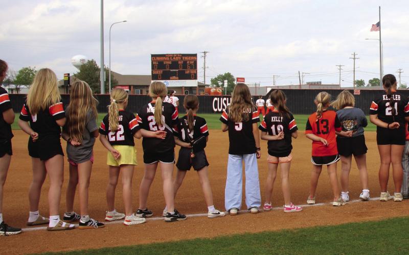 Cushing Tiger youth athletes join the varsity Lady Tigers on the field for the Star Spangled Banner during the youth night game against Chandler last week. Photo by Allie Prater.
