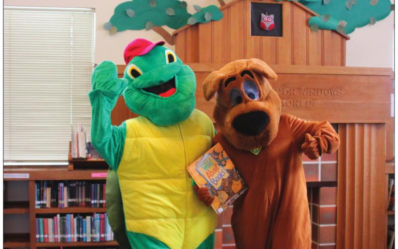 Beloved children’s book characters, Scooby-Doo and Franklin the Turtle, hold one of the many books available at the Cushing Public Library.