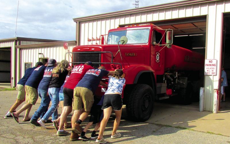 Cpt. Patrick Johnston, Lt. Jansen Callanan, Chief Mike Callanan, Asst. Chief Tory Sweet, Captain Casey Walters, and firefighters Ron Pendergraff, Kyle Wolff, Hailey Johnston, Samantha Dixon, and Jarrod Molloy as well as community members came together to push Tanker 1 into the firehouse during the traditional push-in ceremony held on Sept. 24. Photo by DeAnna Maddox