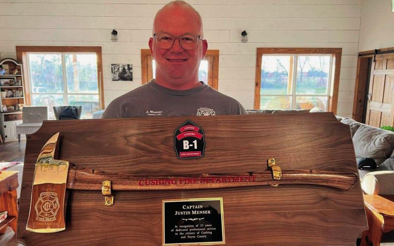 Newly retired Cushing Fire Department Captain Justin Menser displays a golden axe given to him to commemorate 25 years of service.