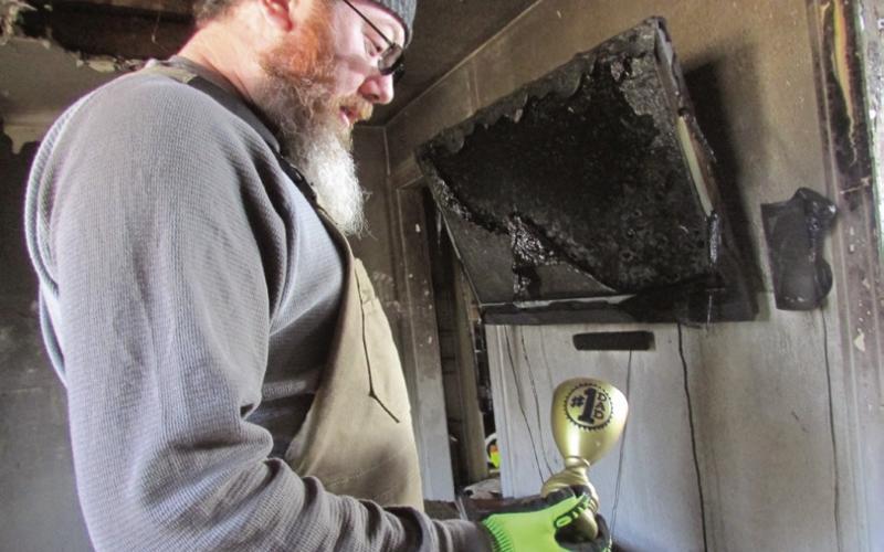 Jeremy Fincher holds a “worlds best dad” trophy while standing in the ruins of his family’s home.