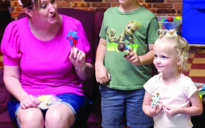 Toddler Music Time instructor Regina Brown shows siblings Parker and Blake Stacy how to use finger puppets during the first Toddler Music Time of the summer held at the Cushing Public Library Monday, June 17. Photo by Raynee Howell.