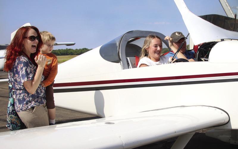 CHS aviation teacher Dr. Jessica Sigle and her son Timothy share their excitement with aviation student Emery Turner as she sits in the cockpit of Matt Steward’s RV kit plane after logging her first flight hour.
