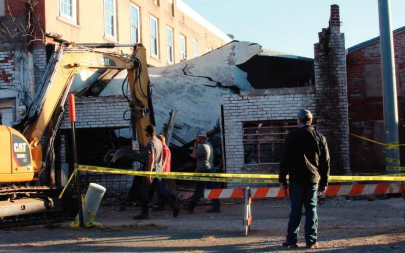 A crew from TKO Construction works to take down a collapsed building at 110 West Broadway in Cushing Monday.