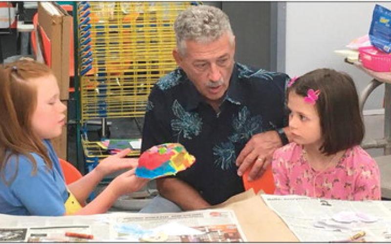 Representative John Talley discusses how to make a mask with Hadley Marshall (left) and Piper Sigle during the last week of the most recent Cushing Art Camp held at Cushing Middle School.