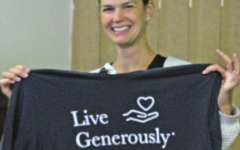 Alycia Finkbeiner holds up a shirt donated by one of the local area churches to be included in the care totes the women assembled on Nov. 12.