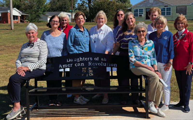 Pictured from left are DAR members Rosalind Detrich, Lee Denney, Karon Brown, Debbie Cochran, Grace Ellsworth, Sharon Baker, Julie Jones, Rosalie Vaught, Sue Cline, Nancy Griffin, and Charlotte Chesrow with a recently installed iron bench in Cushing commemorating the nation’s upcoming 250th anniversary.