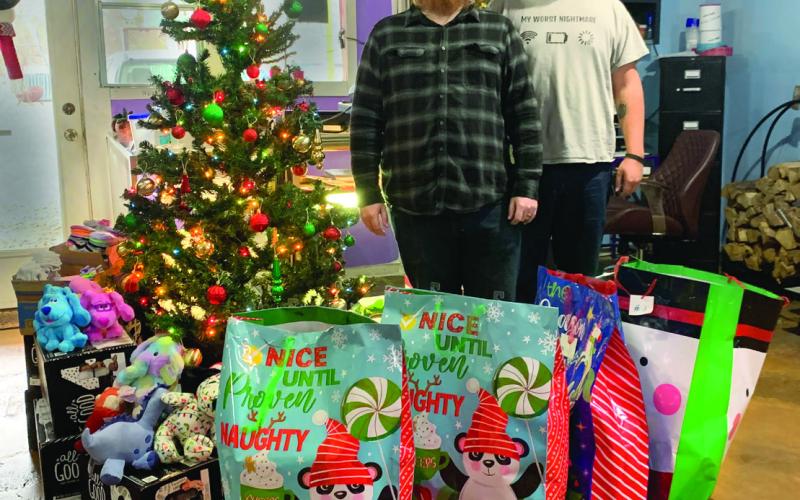 Arcane Panther Tattoo Studio owner and tattoo artist Jeremiah Smith, and apprentice Bradley Couch stand next to the gifts that have been donated so far for the third annual Toys for Tats Toys Drive. Photo by Allie Prater
