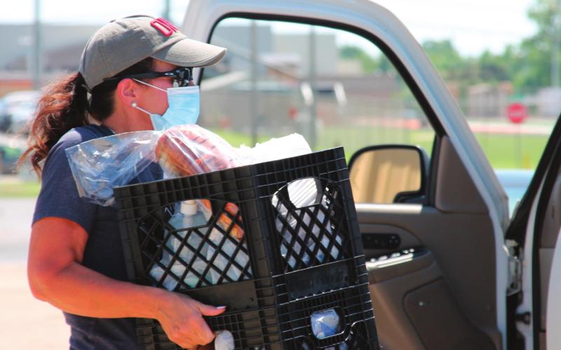 Shelly Wilson works hard carrying crates filled with groceries out to one of the participants during the Our Daily Bread event on Aug. 25 at the Cushing Community Food Pantry.