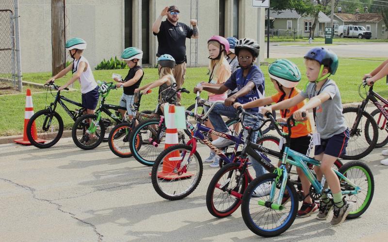 Cushing police and corrections officers teach the recipients of new bikes how to ride safely during the 12th Annual Brandon Hise Memorial Bicycle Rodeo at City Hall Saturday, June 1. Photo by Raynee Howell.
