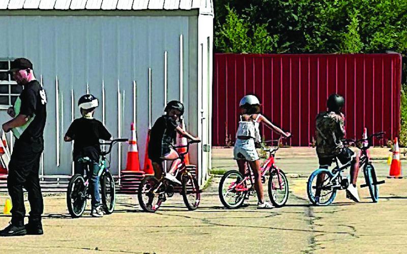 Participants of the Brandon Hise Memorial Bike Rodeo make their way through an obstacle course as Cushing Police Department members monitor and instruct in safe practices.