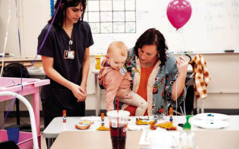 Advanced Health Careers Instructor Brandi Fisher interacts with a young Central Tech supporter alongside a student during open house.