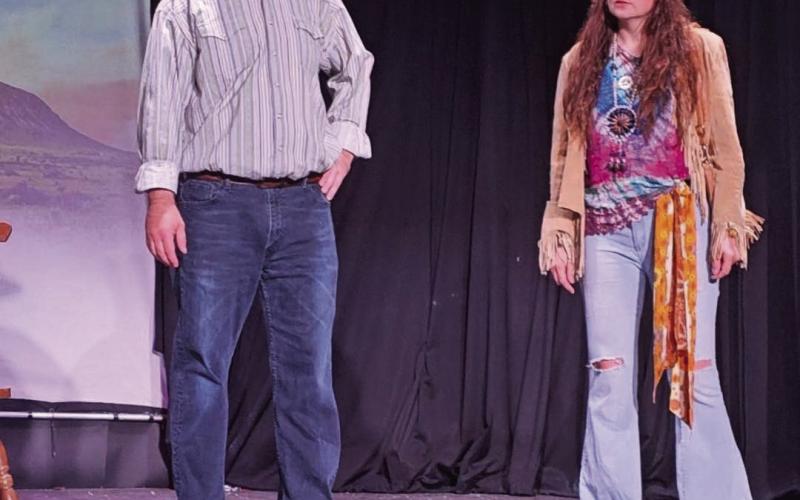 Chris Reid and Krystle Hutchko stand on center stage during the play “Hippies, Housewives, and Watering Holes” — which Reid also directed. Hutchko was also selected as the Judge’s Choice for Best Costume.