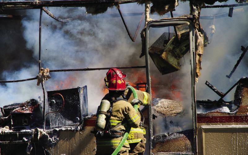 Members of the Cushing Fire Department work to extinguish a burning RV on East Vine. Photo by Allie Prater