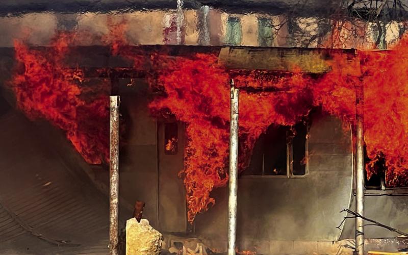 Flames completely engulf a mobile home attached to the former Laundromat. Photo by J. D. Meisner