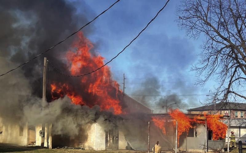 Flames find their way through the gables of the old laundromat as fire spreads to the attached mobile home. Photo by J. D. Meisner