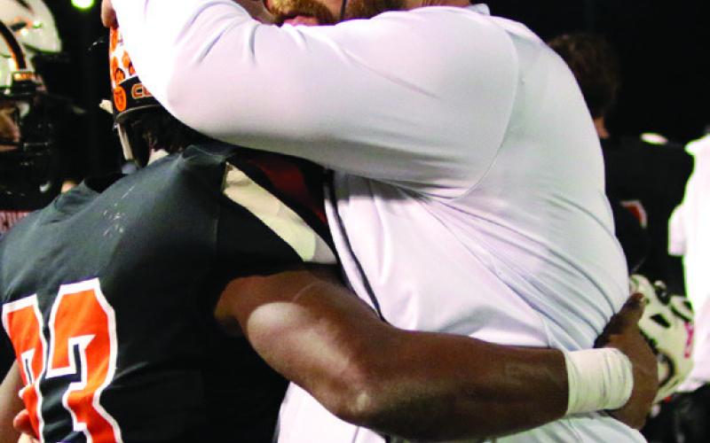 Above: Noah Jones cuts through the ElK City defense. Right: Head Coach Rusty Morgan hugs running back Noah Jones on the sidelines after Cushing punched their ticket into the state finals.