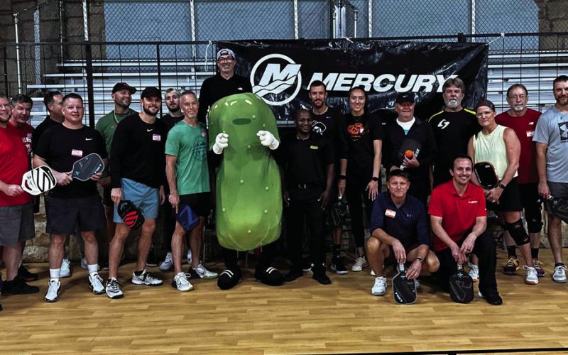 Tournament participants pose with Big Dill the mascot for Pickleman’s Gourmet Cafe, in Stillwater after the Mercury Marine Fourth Annual Pickleball Tournament.