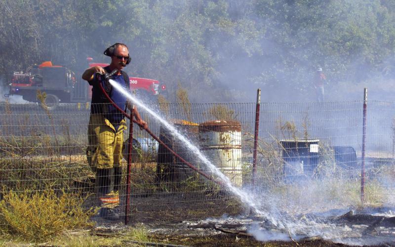 Cushing Fire Department Lieutenant James Blevins uses a tanker hose to cool off one of the last hotspots following the cooperative efforts of several local departments to put out a grass fire close to Agra last Friday, Sept. 30. Photo by DeAnna Maddox