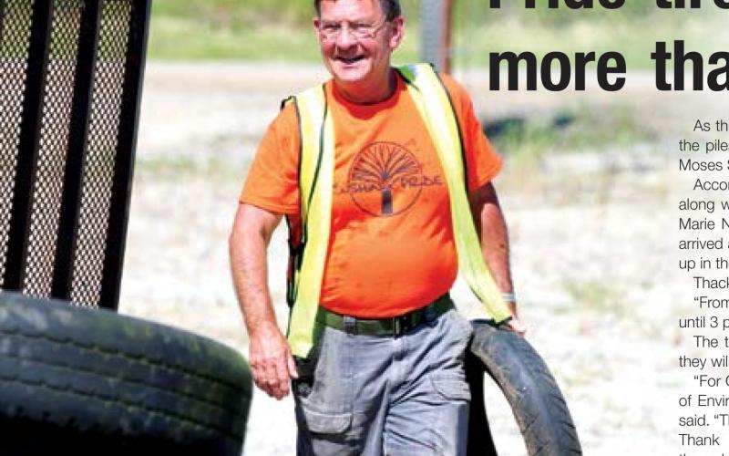 John Moran unloads a motorcycle tire from a trailer during Cushing Pride’s tire recycling event Saturday.