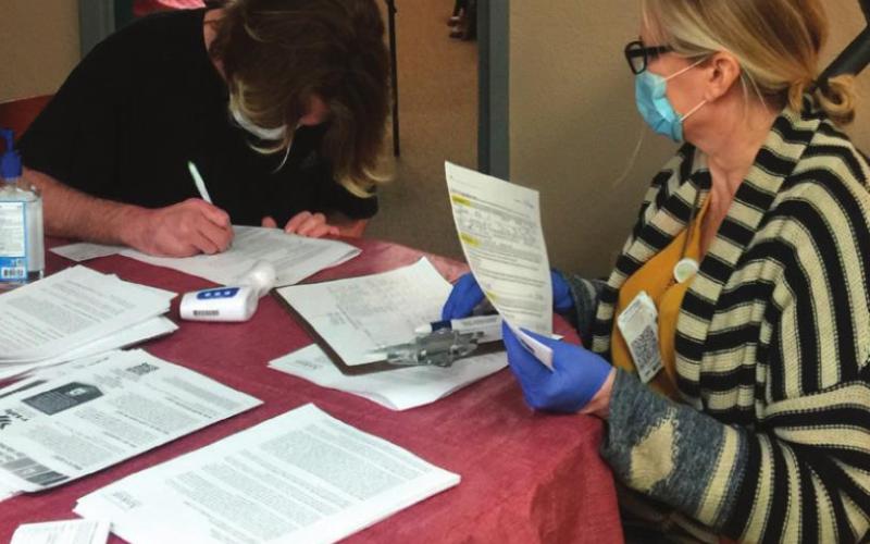 Kerri Marks, Director of Operations at Hillcrest Hospital Cushing receives documentation from a Cimarron Towers resident as more wait in the hallway.