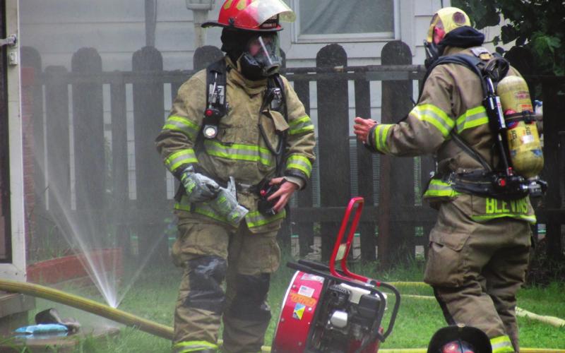 Firefighters Dakota Shadowen and James Blevins takes a moment to catch their breath before continuing to work against the fire at 1002 West Broadway on Tuesday, May 24. Photo by DeAnna Maddox