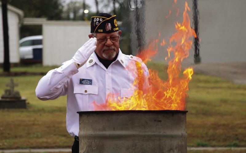 Legionnaire Tim Potter salutes the flags as they burn. Photos by Allie Prater