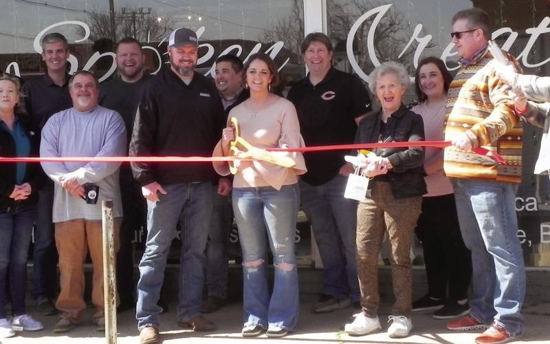 Members of the Cushing Chamber of Commerce stand with the owners of Spoken Creation, Kyle and Rachel Williams, during the ribbon cutting ceremony in front of their new business on Cleveland. Photo by Cayla DeHaas.