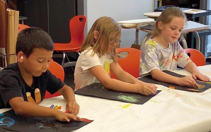 Jacob Ketchum, Olivia Worthy, and Audrey Massey work on their pastel drawings.