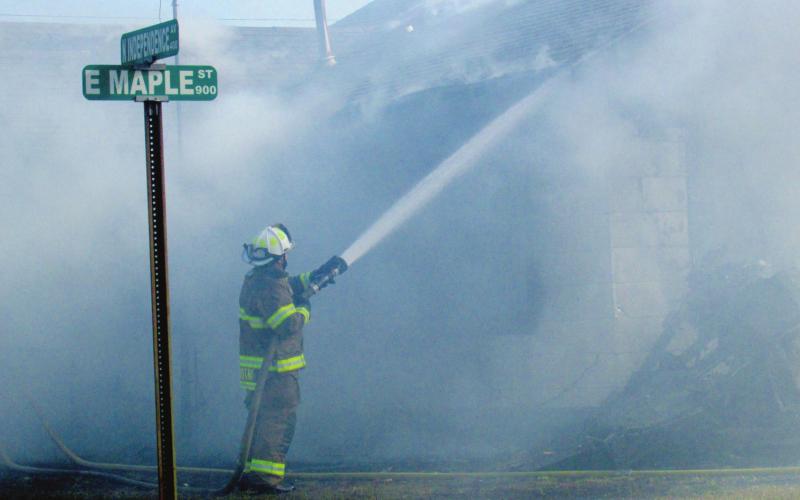 Deputy Fire Chief Dalton Novotny keeps a steady stream of water running over the home on the corner of Maple and Independence as the fire comes under control. The Cushing Fire Department stayed on scene for two hours to watch for hot spots and possible flares.