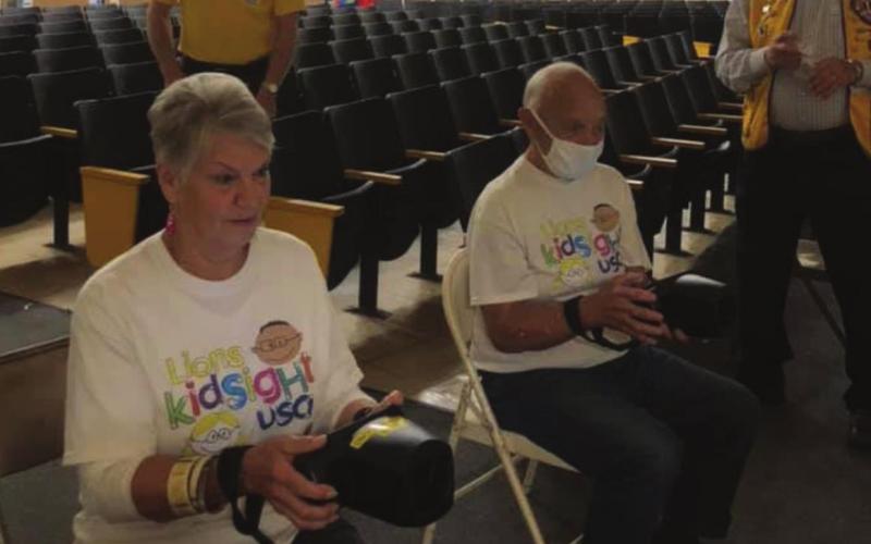 Cushing Lions Club members Lou Griffi n and Jim Pickard hold steady as they handle the cameras for Oak Grove School students being screened, while Tom Cummings and Russell Thurman supervise and hand out stickers in the background.