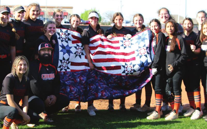 The entire Lady Tiger slowpitch softball team surrounds Assistant Coach Josh Encinas (kneeling) after he received his Quilt of Valor between games last Tuesday.