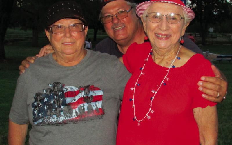 Carol and Daryl Arfman stand beside Marie Solomon in Cushing Memorial Park celebrating by donning American flag colors and watching the annual firework display from Cushing Fire Department.