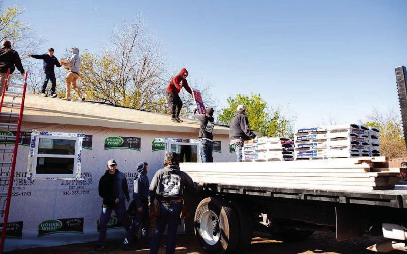 Construction students at Central Tech load shingles on the roof of the house they are building.