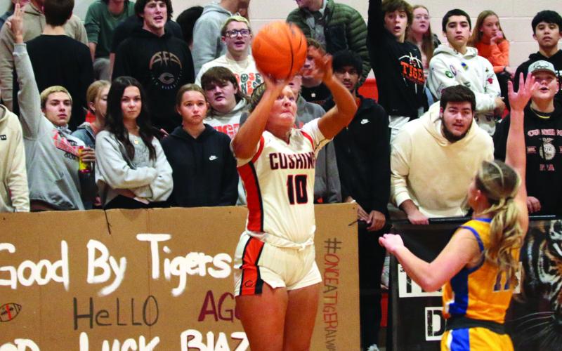 Katy Jones puts up a three pointer from the corner as members of “The Jungle” Cushing’s notorious student section, put their own energy into the shot.