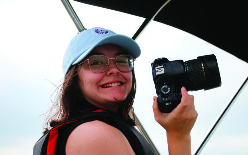 Raynee Howell smiling, camera in hand, while doing an ‘on the job’ interview with an USACE ranger on the lake patrol boat at Keystone Lake in May. Photo by Allie Prater
